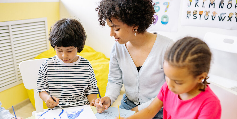 Een kinderopvangmedewerker met twee kinderen.