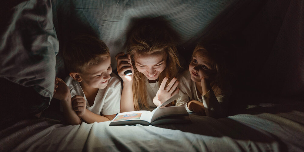 Een moeder leest haar kinderen voor.