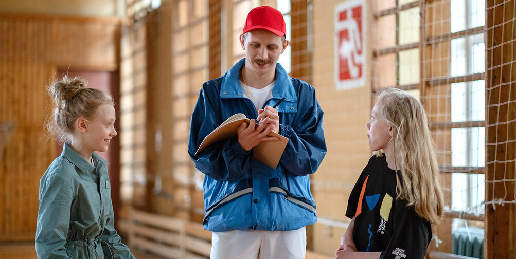 Gymleraar met twee leerlingen in een gymzaal